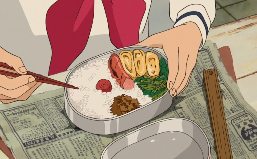 A still from the Studio Ghibli film From Up on Poppy Hill showing hands, chopsticks and lunch in a lunch box.