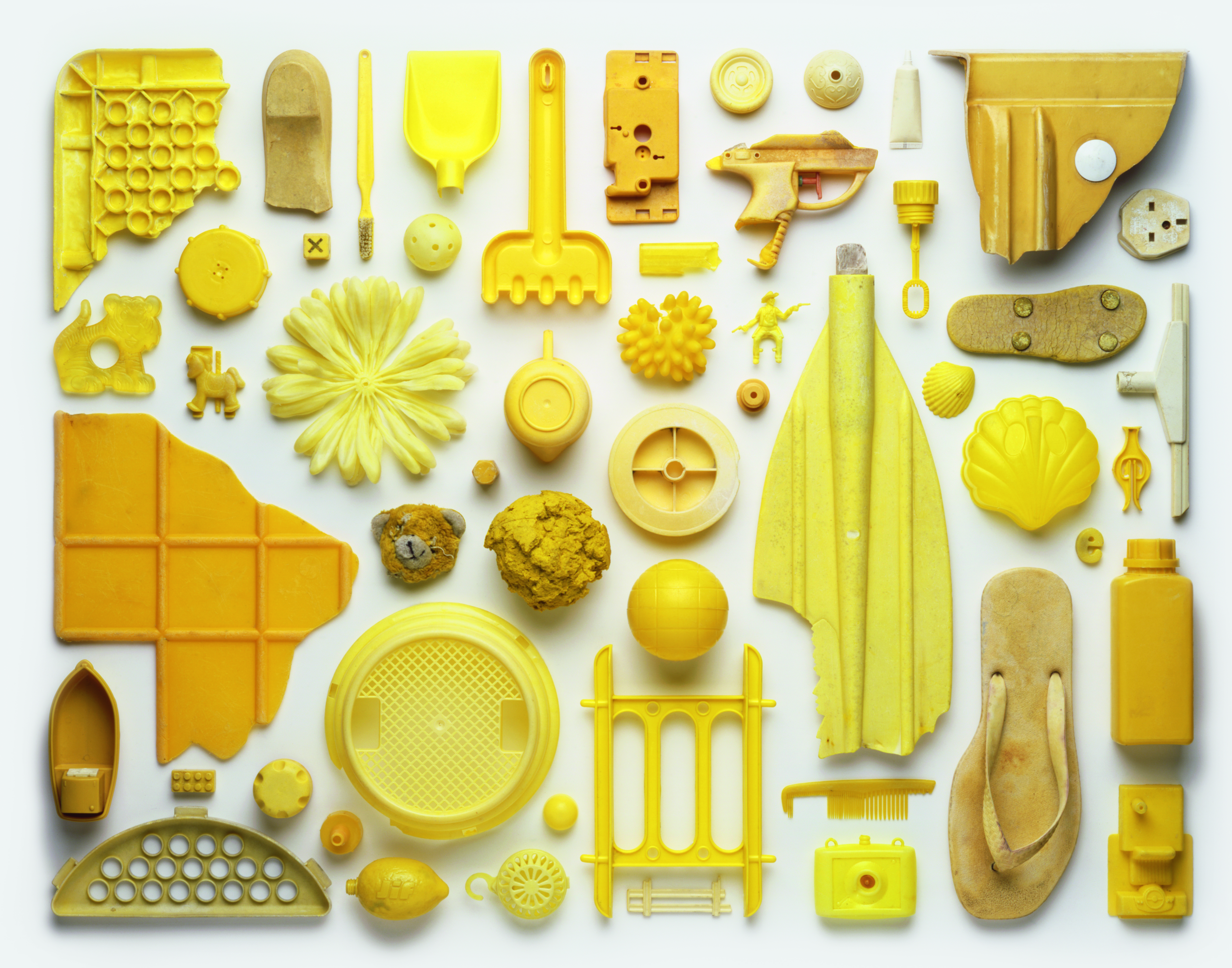View from above of an artwork that is an arrangement of yellow-coloured pieces of plastic pollution washed up on a beach in the UK