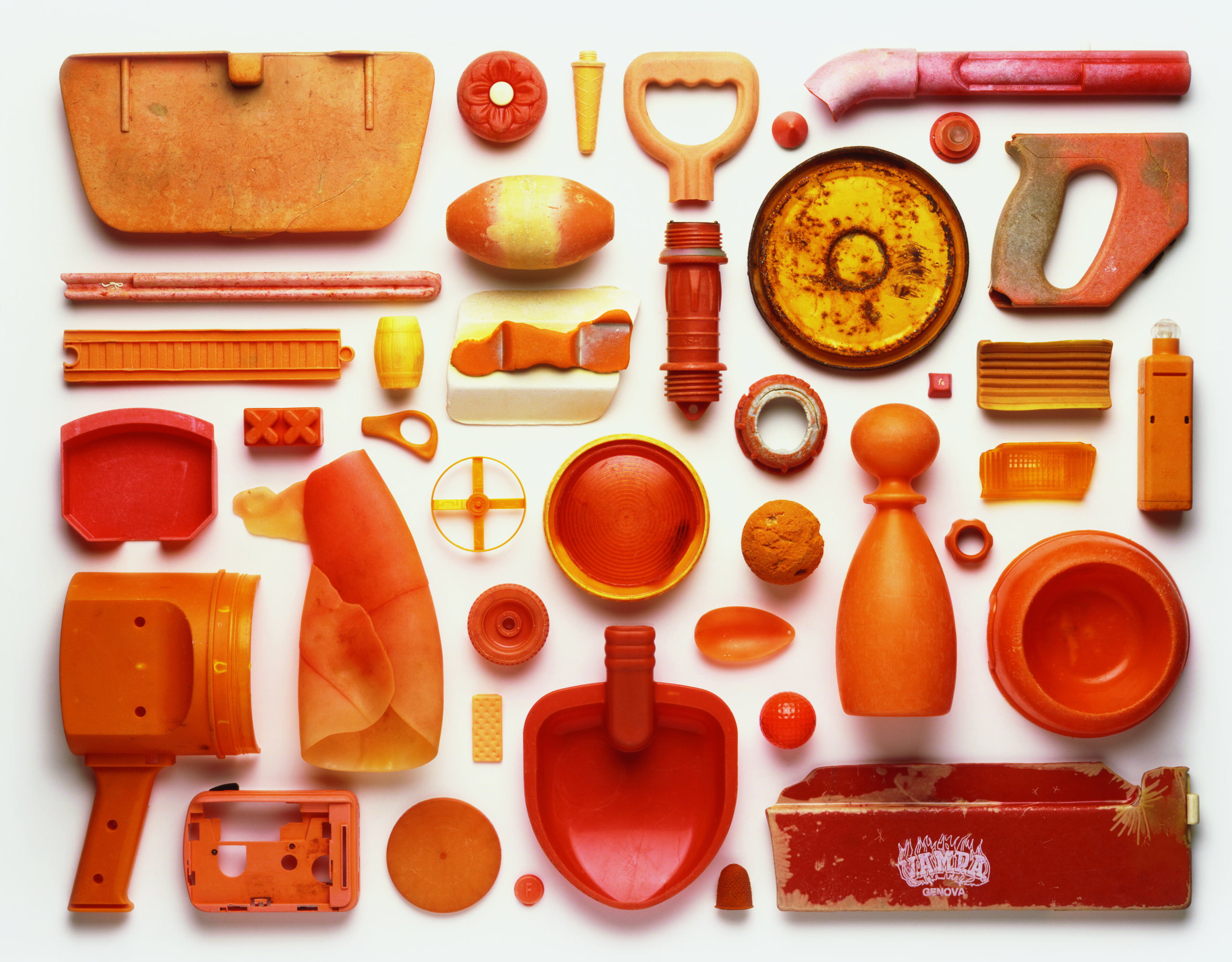 View from above of an artwork that is an arrangement of orange-coloured pieces of plastic pollution washed up on a beach in the UK