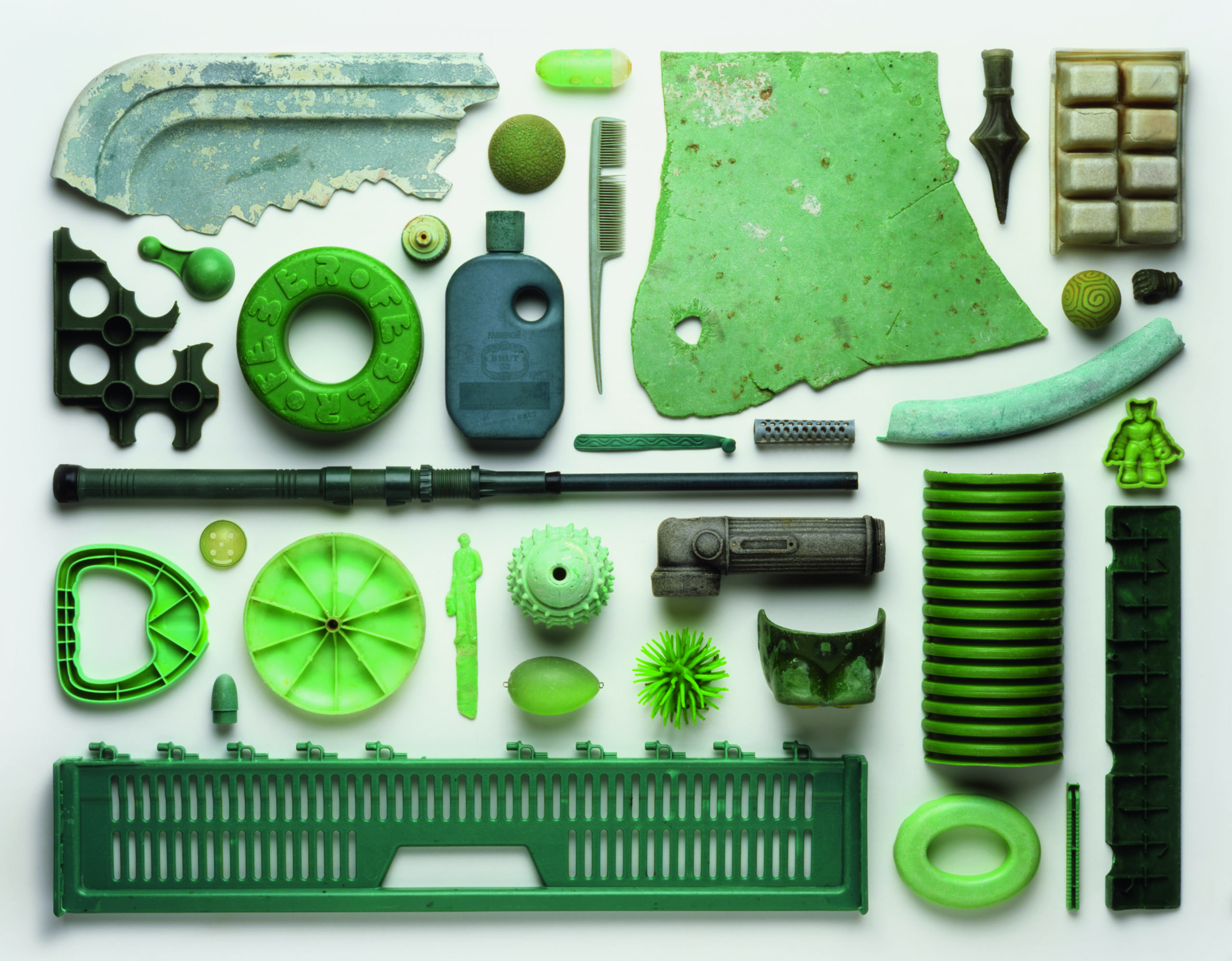 View from above of an artwork that is an arrangement of green-coloured pieces of plastic pollution washed up on a beach in the UK