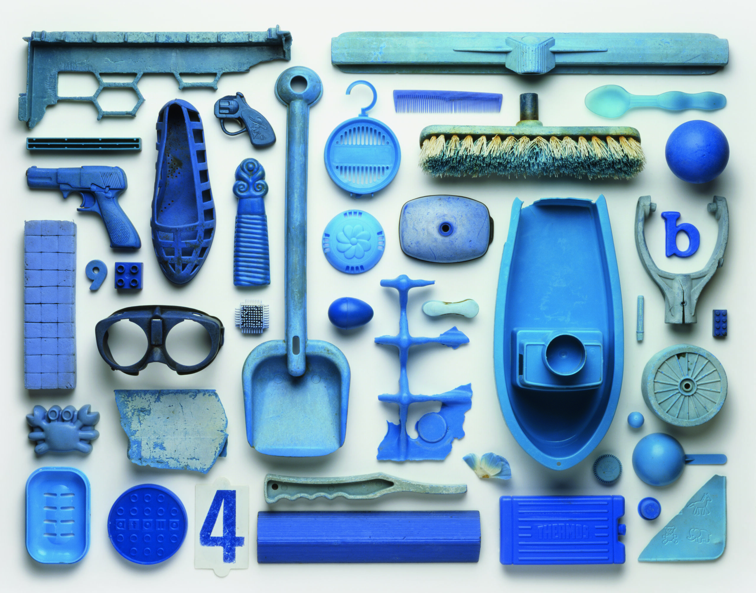 View from above of an artwork that is an arrangement of blue-coloured pieces of plastic pollution washed up on a beach in the UK