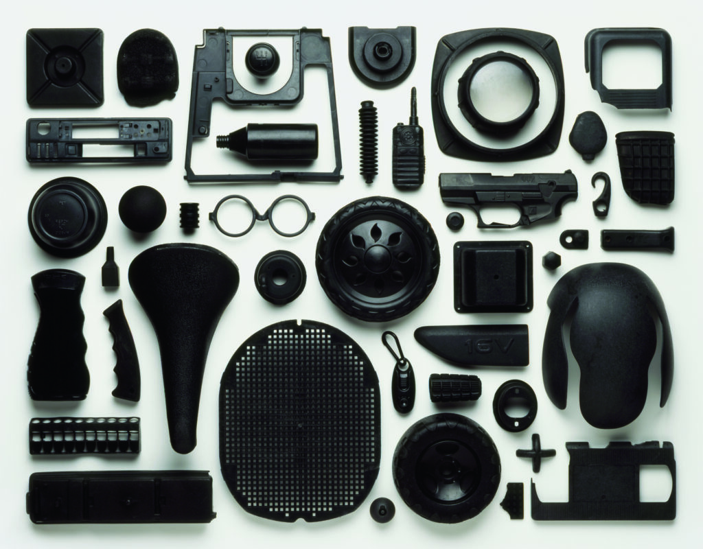 View from above of an artwork that is an arrangement of black-coloured pieces of plastic pollution washed up on a beach in the UK