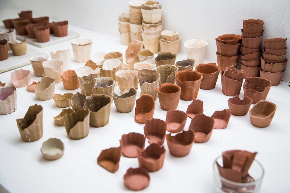 A photo of lots of half-eaten small edible clay pots in an exhibition
