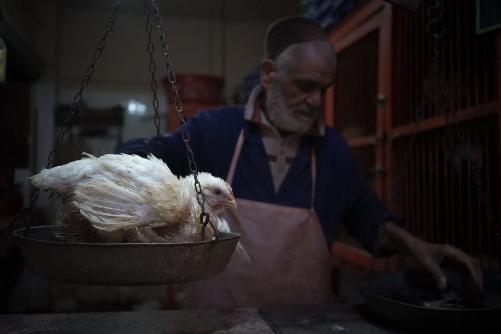 man selling a chicken in a Moroccan market
