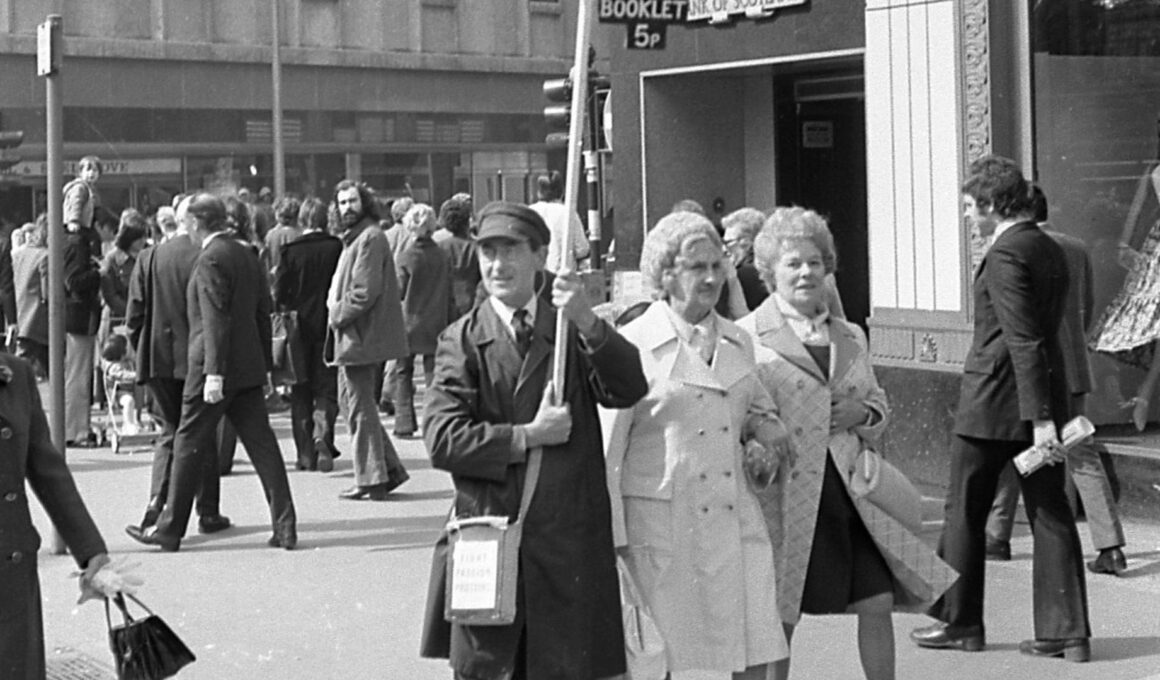 b/w photo of man walking in a street 1970s