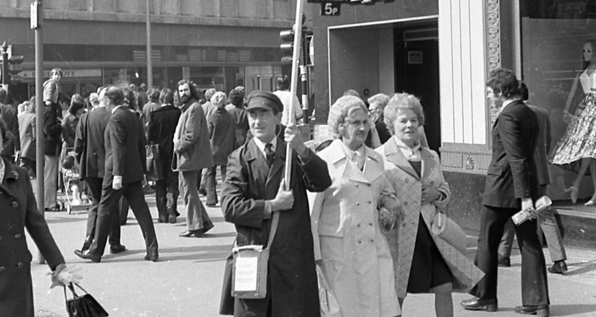 b/w photo of man walking in a street 1970s
