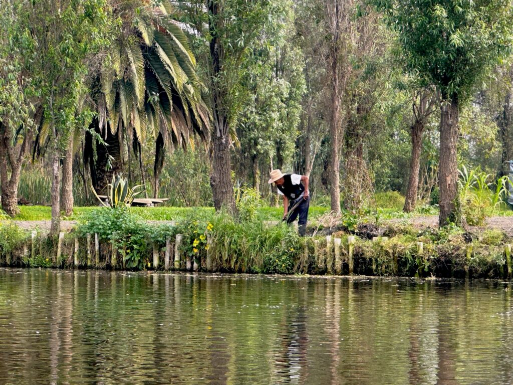 A man in a hat digging beside water