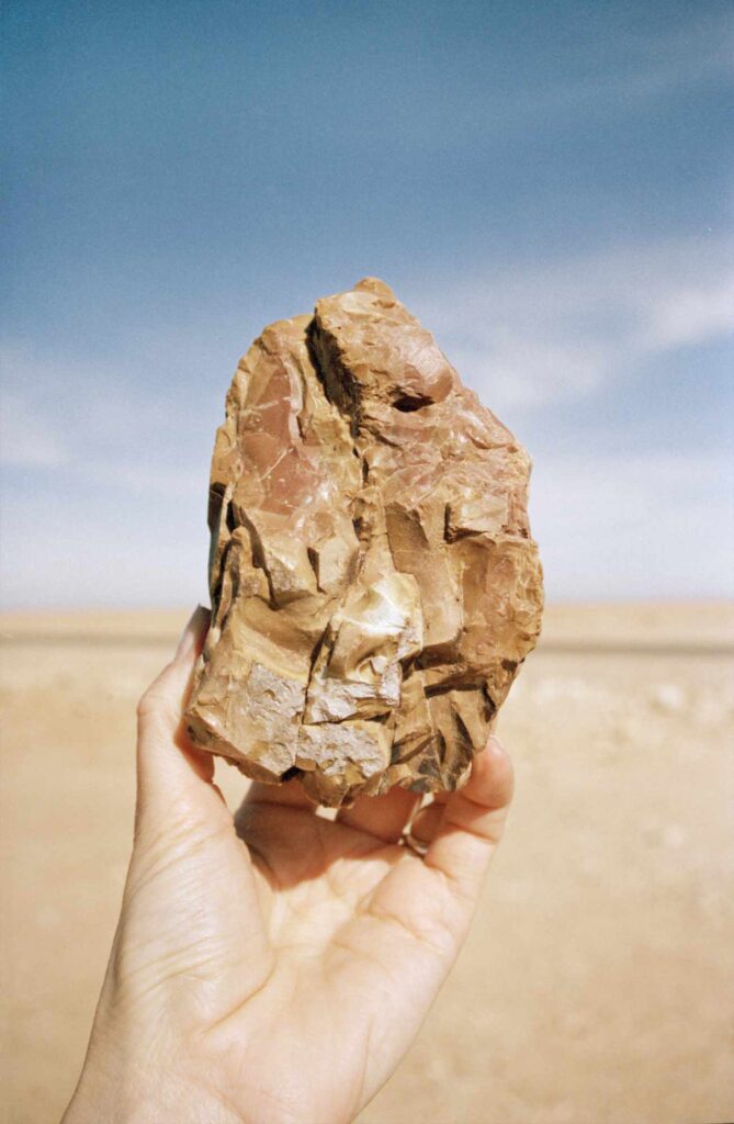 Hand Holding a large chunk of rock from the area surrounding the spoil heaps of the Bou Craa phosphate mine, in Moroccan-occupied Western Sahara. Image © and courtesy of Crystal Bennes